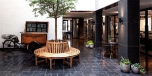 Modern restaurant interior with wooden benches, stone tree, and metal accents