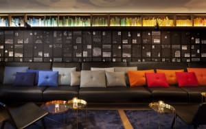A modern hotel bar featuring a comfortable seating area with leather cushions on a long, black leather sofa.