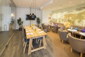 A minimalist conference room featuring a long wooden table, modern seating, and decorative plants.