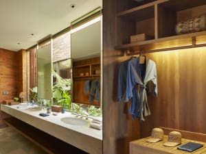 A modern bathroom with wooden elements, including a wooden vanity, shelves, and a hanging robe.