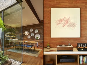 A modern interior design with a wooden wall, a white canvas with an abstract design, and a turntable on a wooden shelf.