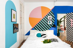 A bedroom with a colorful geometric mural painted on the wall