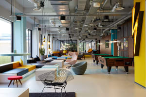 A modern playroom featuring concrete flooring, industrial-style lighting, and a mix of comfortable seating and recreational a