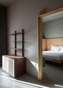 Modern minimalist bedroom featuring a wooden headboard and flooring, with a minimalist design and white bedding.