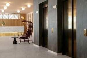 Modern hotel lobby featuring concrete, marble, metal, glass, and wooden finishes.