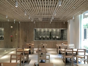 A modern restaurant with wooden tables, chairs, and ceiling. Features include wooden walls and flooring, and stainless steel 
