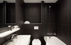 Minimalist bathroom featuring black tiles, a white countertop, and chrome fixtures.