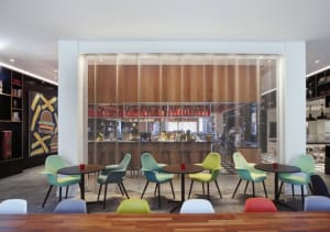 Modern cafe bar with metal netting, colorful chairs, and tables.