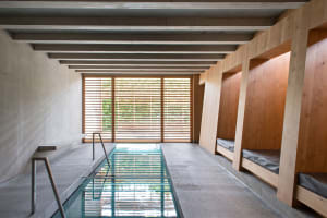 An indoor minimalist spa with concrete walls and wooden benches.