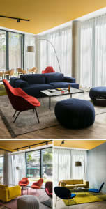 Contemporary living room featuring a navy blue sofa, red accent chair, and floor lamp, with fabric curtains and a yellow acce