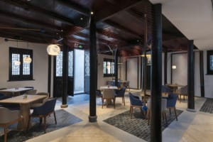 Modern restaurant interior with wooden tables, glass walls, textile ceiling, and stone and concrete accents.