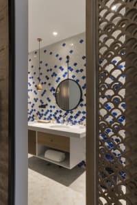 Modern minimalist bathroom with circular mirror, floating vanity, and blue and white scallop tile pattern on the wall