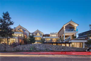 Modern residential building with stone exterior, wooden accents, and glass windows.