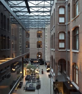 Indoor hotel lobby featuring exposed brick walls, glass walls, and modern furniture.