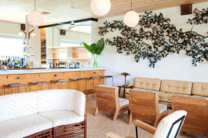 A mid-century bar and lounge interior with wooden furniture, leather seating, and a bar counter.