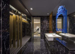 A modern bathroom with black marble walls and a glass partition.