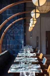 Modern restaurant interior with wooden arches, glass pendant lights, and concrete walls.