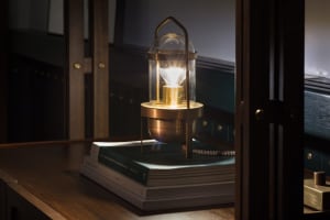 A metal and glass industrial lamp placed on a pile of books.