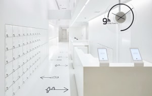 A minimalist commercial space featuring a white interior with white lockers, white cubicles, and a white reception desk.