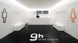 A minimalist white office reception area with black flooring and detailed signage.