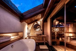 Modern bathroom features wooden accents and a freestanding bathtub under a skylight.