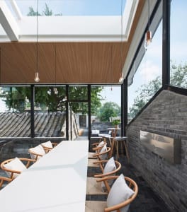 Modern minimalist restaurant interior with wooden furniture and large glass windows.