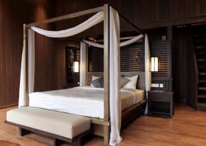A stylish modern bedroom with a wooden canopy bed and white curtains.