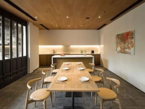 A modern dining room with wood paneling, featuring a long wooden table set for four people.