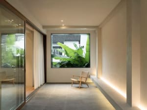 Modern living room with concrete flooring, wood furniture, and large glass windows.