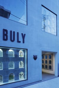 A modern storefront with a blue glass facade displaying decorative elements through arched windows.