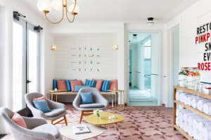A modern spa relaxation room with ceramic tile flooring, comfortable seating, and a wall of instruction posters.