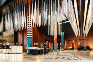 Contemporary hotel lobby featuring polished concrete flooring, wooden panels, and glass elements.