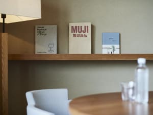 A modern interior with a wooden shelf displaying three books.