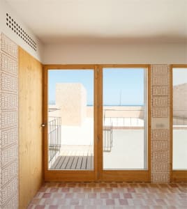 A minimalist residential balcony featuring wooden doors and tiled flooring.