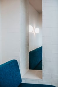 Interior view of a restaurant with white brick walls, concrete flooring, and blue fabric seating