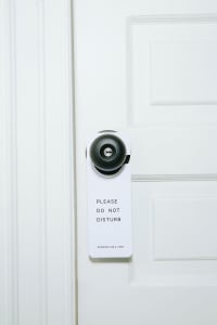 A black and white 'Please Do Not Disturb' sign attached to a white door.