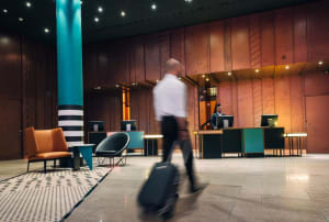 Modern hotel lobby with metallic wood paneling, minimal furniture, and warm lighting.