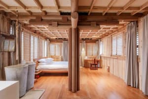 Minimalist bedroom with wooden furniture, white bedding, and large windows