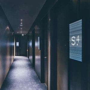 Dark wooden hotel corridor with a digital display panel showing the number 34.