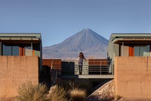 Person standing on a concrete balcony overlooking a mountainous landscape.