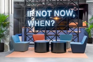 Industrial-style office lobby with metal frames, concrete walls, and upholstered seating.