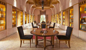 A library interior with warm wood furniture and shelves filled with books and decorative items.