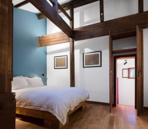 A minimalist bedroom with wooden furniture and white bedding.