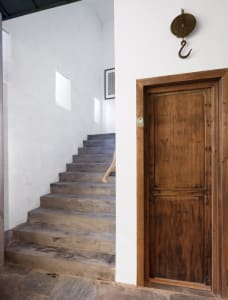 A minimalist staircase with wooden steps, featuring a rustic hook and a framed piece of art in the background.
