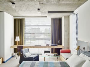 A contemporary bedroom featuring concrete walls, glass windows, and upholstered furniture.