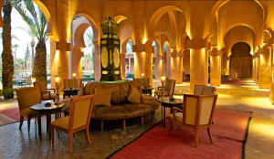 An elegant modern hotel lobby with wooden furniture and fixtures, illuminated by warm lights.
