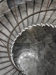 A modern, glass staircase with polished marble flooring.