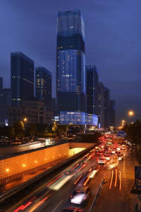 A bustling cityscape featuring modern glass skyscrapers and illuminated streets at night.