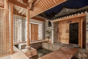 Traditional Chinese courtyard with wooden structures, glass walls, and stone elements.