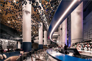 A modern bar interior with metallic decor, glass elements, and concrete surfaces.